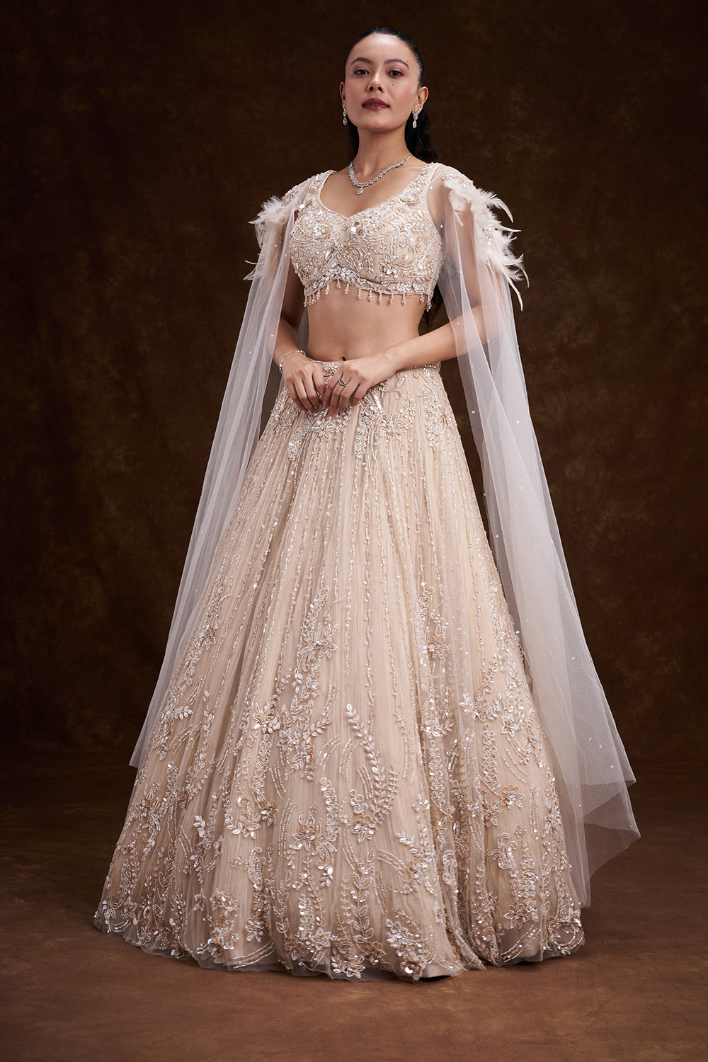 Cream Net Bridal Lehenga with Feathered Shoulder Detail and Embellished Cape