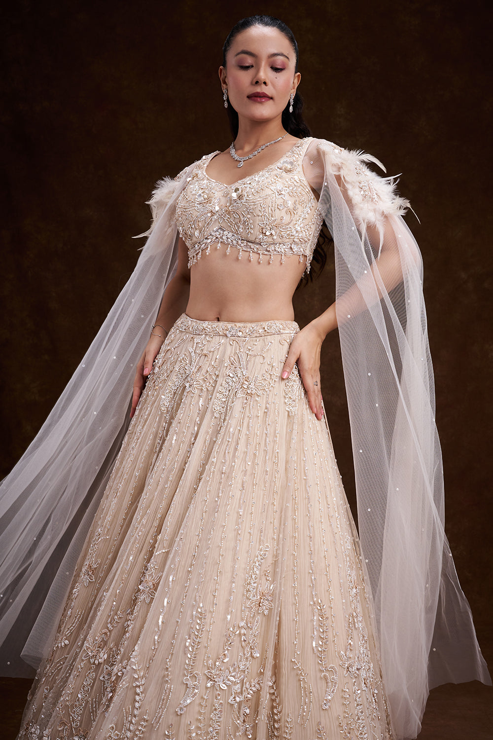Cream Net Bridal Lehenga with Feathered Shoulder Detail and Embellished Cape