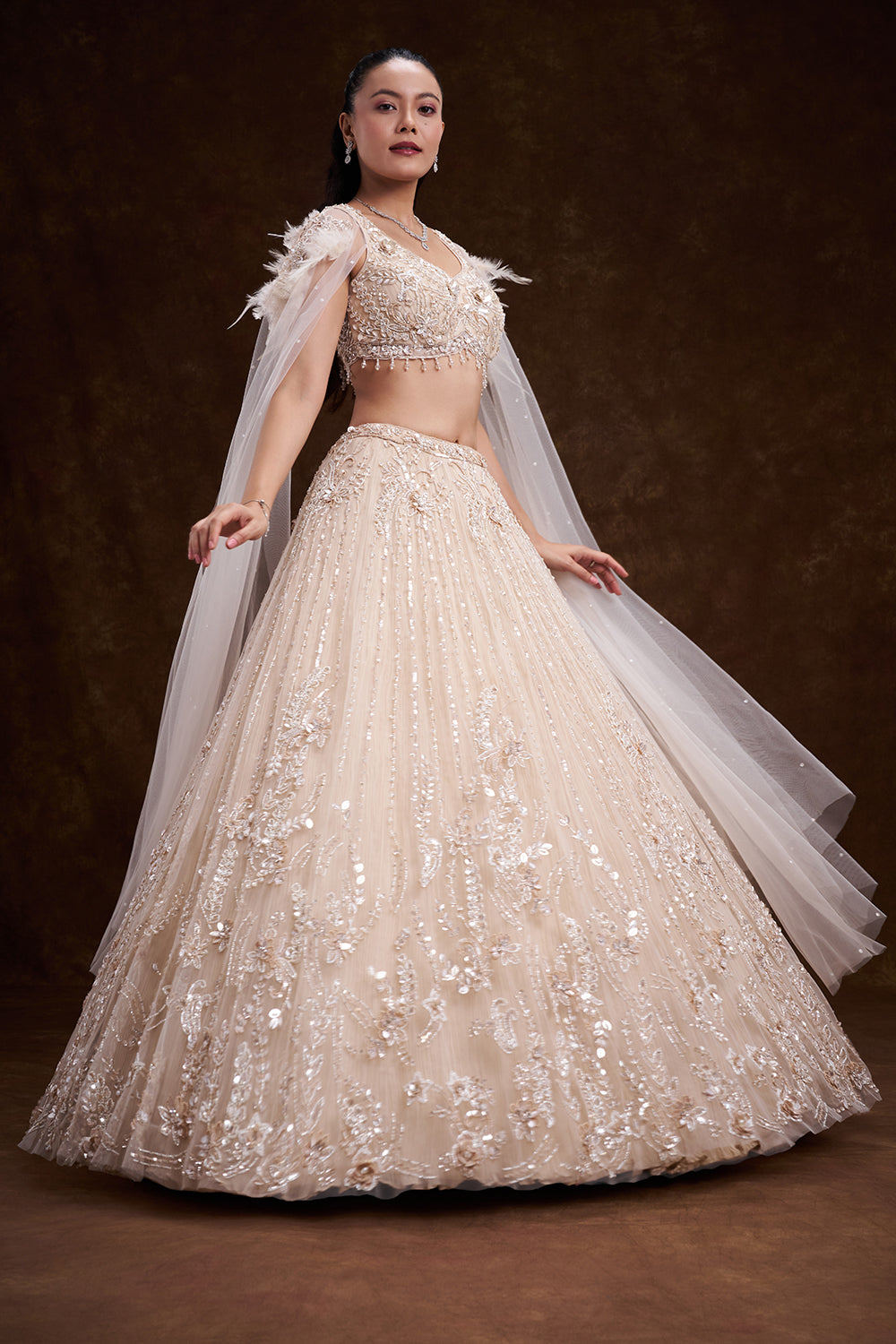 Cream Net Bridal Lehenga with Feathered Shoulder Detail and Embellished Cape